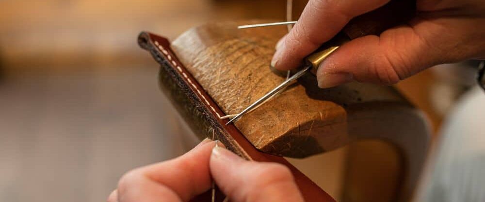 two hands stitching leather
